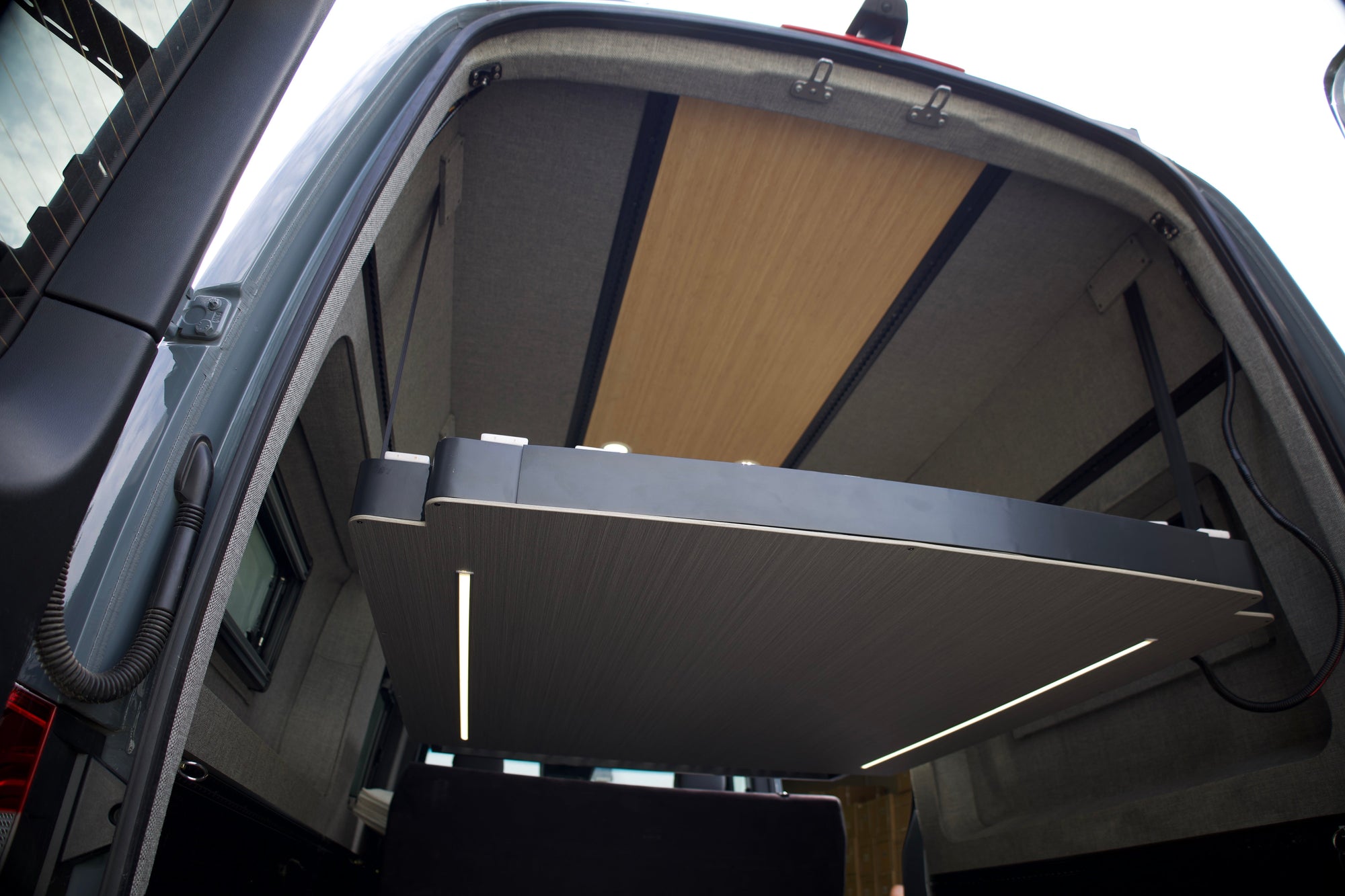 Camper van interior with RoamLabX elevator bed raised above the living space